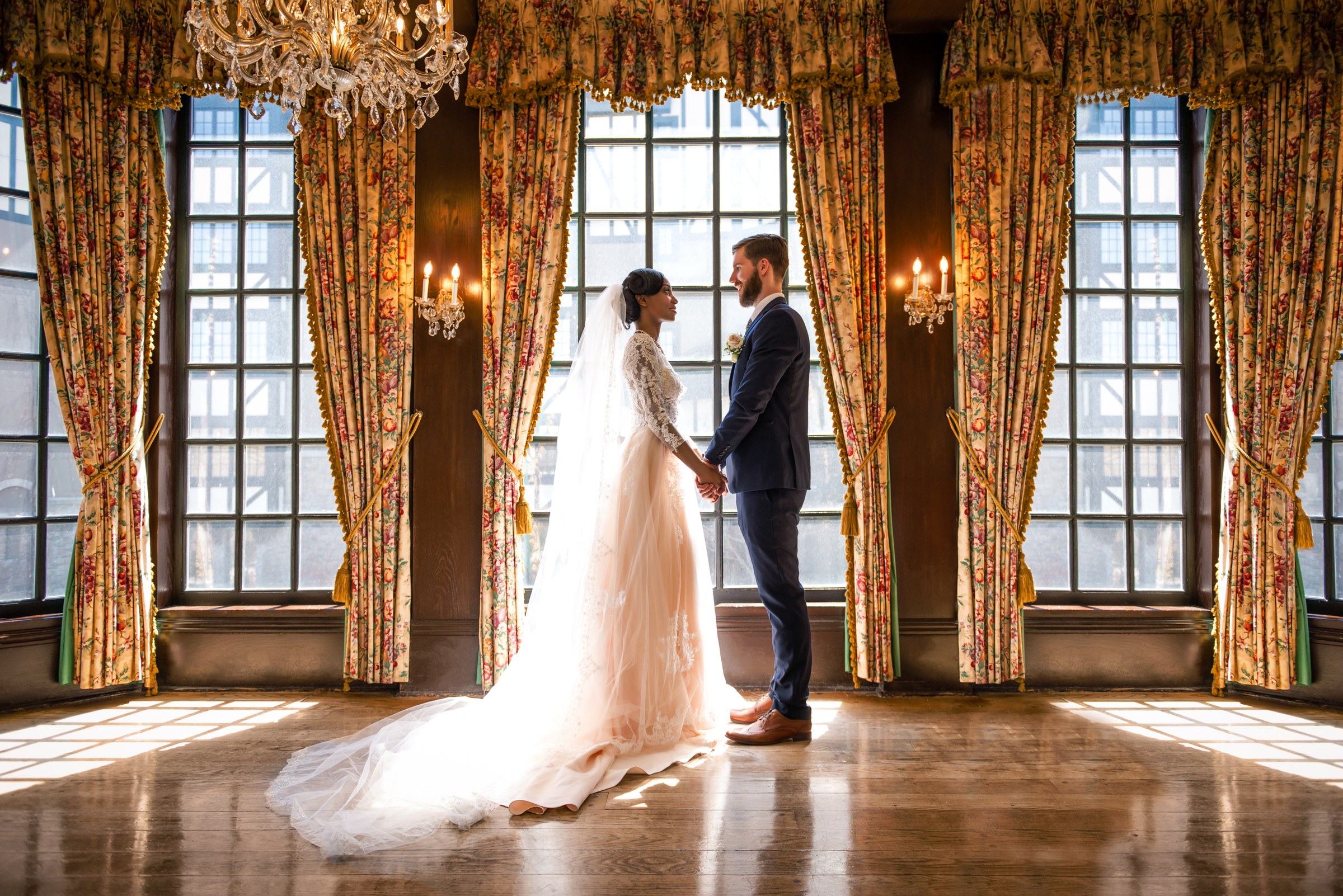 Couple holding hands in a sunlit room with tall windows