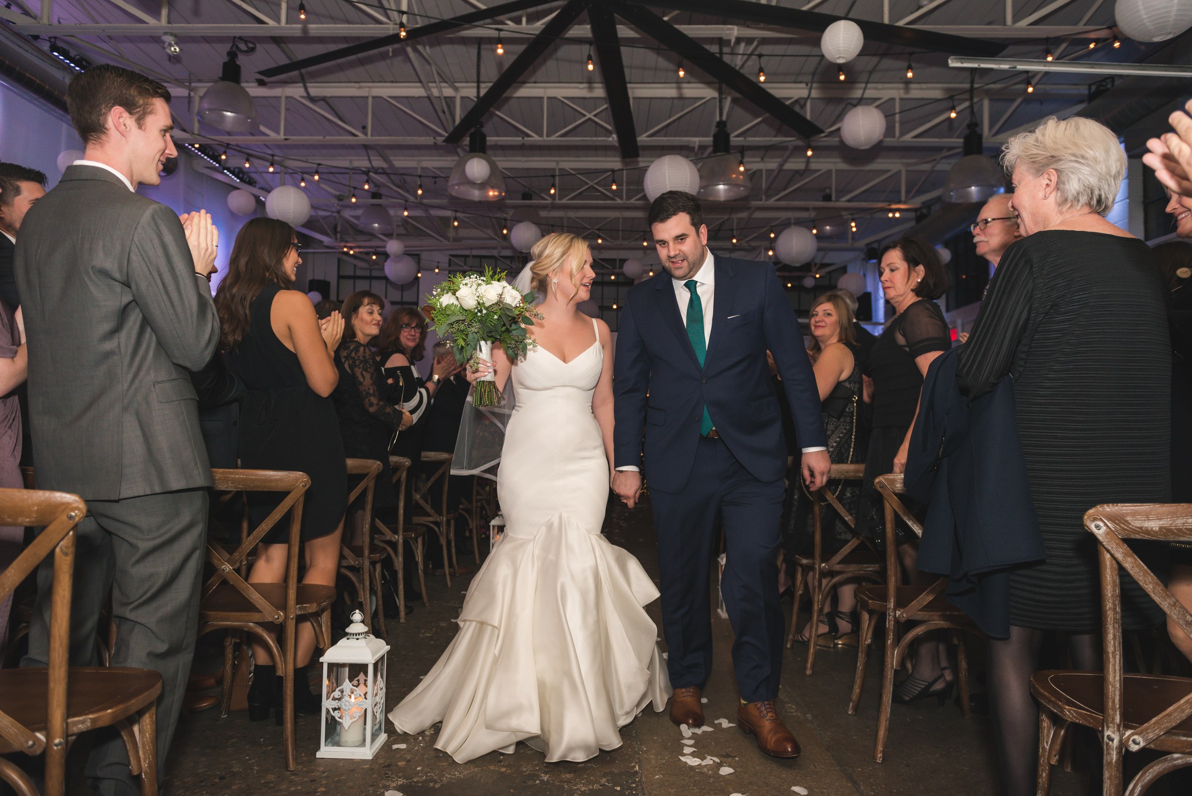 Newlyweds walking down the aisle as guests applaud